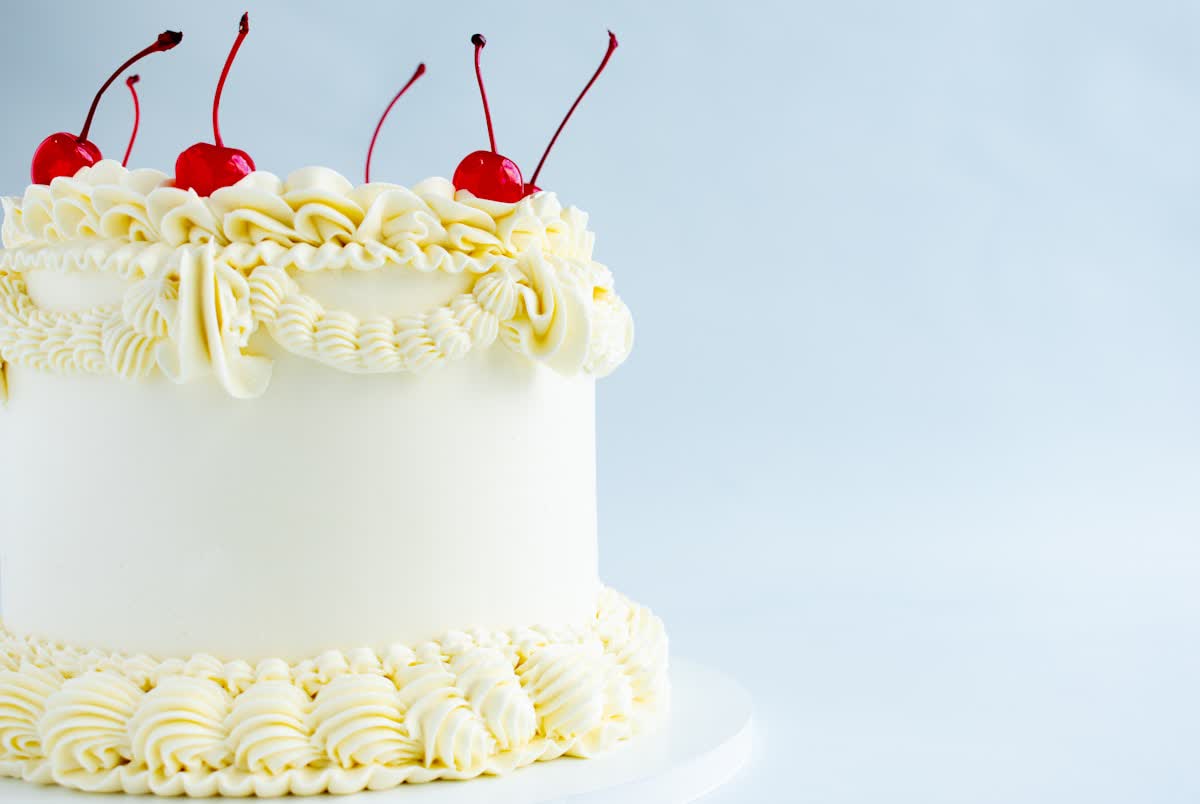 Small vintage-style cake with piped frills and cherries