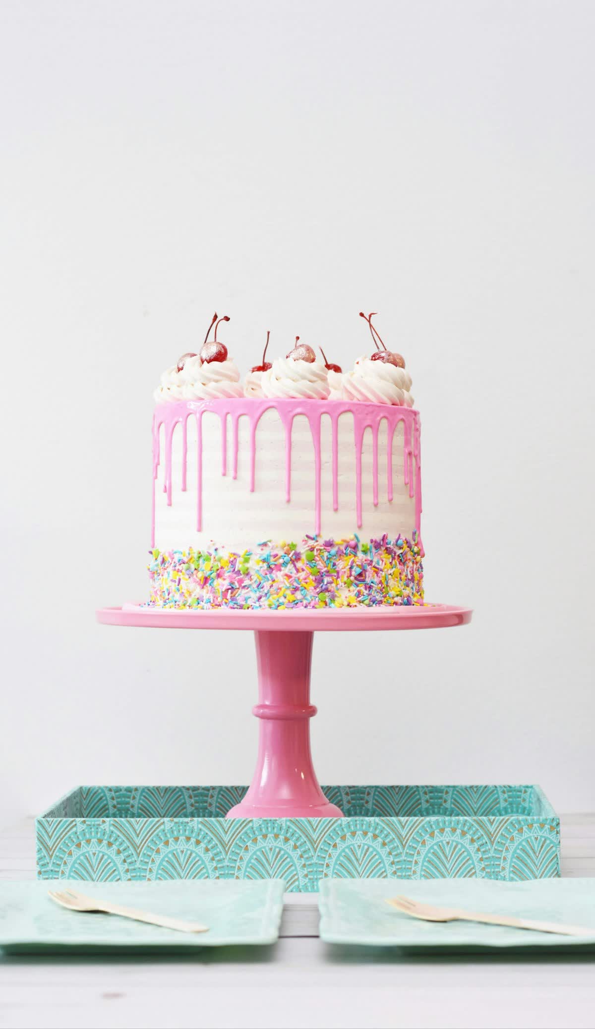 Pink drip celebration cake topped with cherries and sprinkles