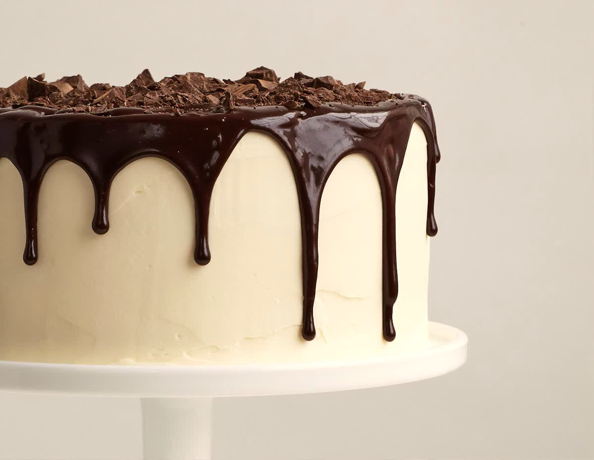 Cake with a glossy chocolate drip over smooth buttercream