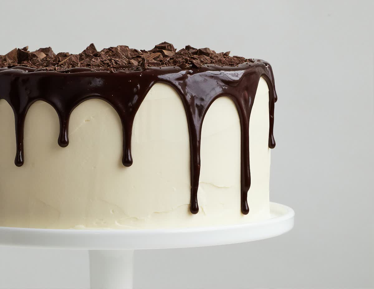 Cake with a glossy chocolate drip over smooth buttercream