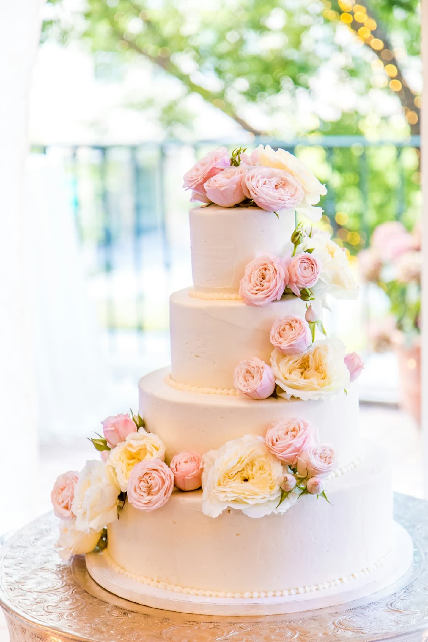 Tiered white wedding cake dressed with fresh roses