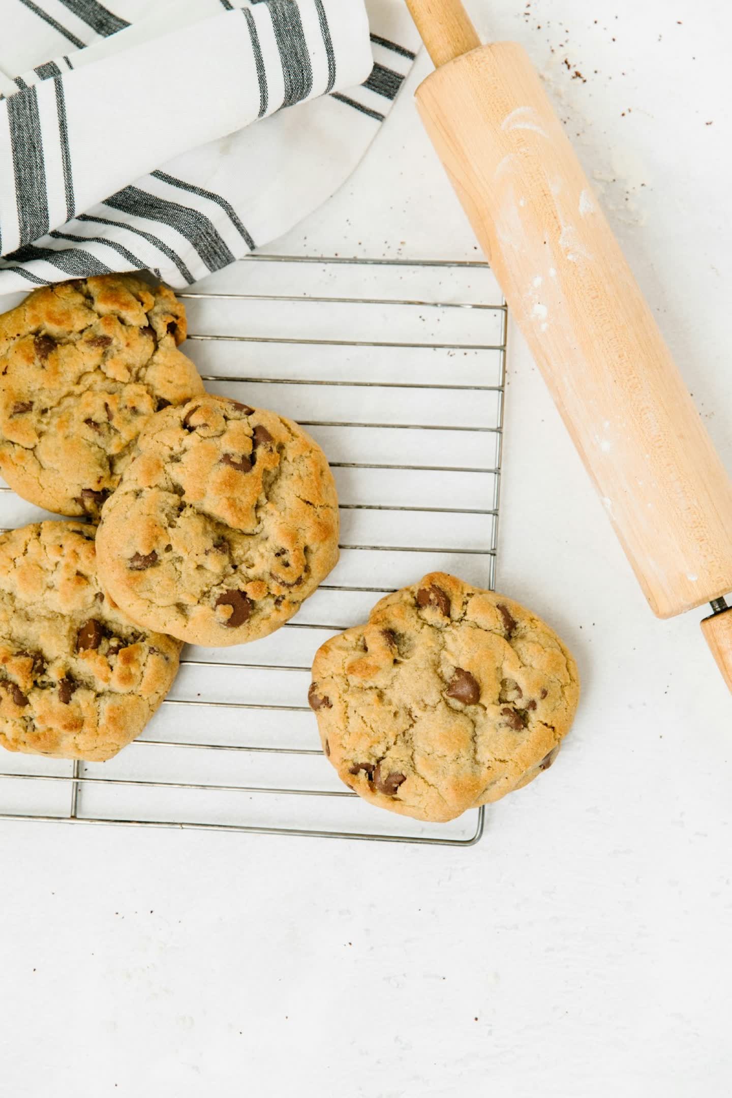 Golden cookies cooling on a wire rack beside a rolling pin