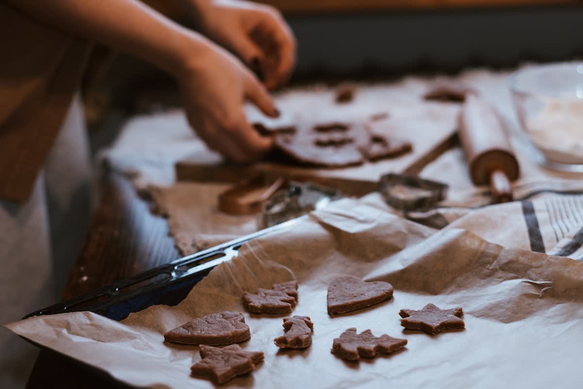 Hands cutting cookie dough into shapes