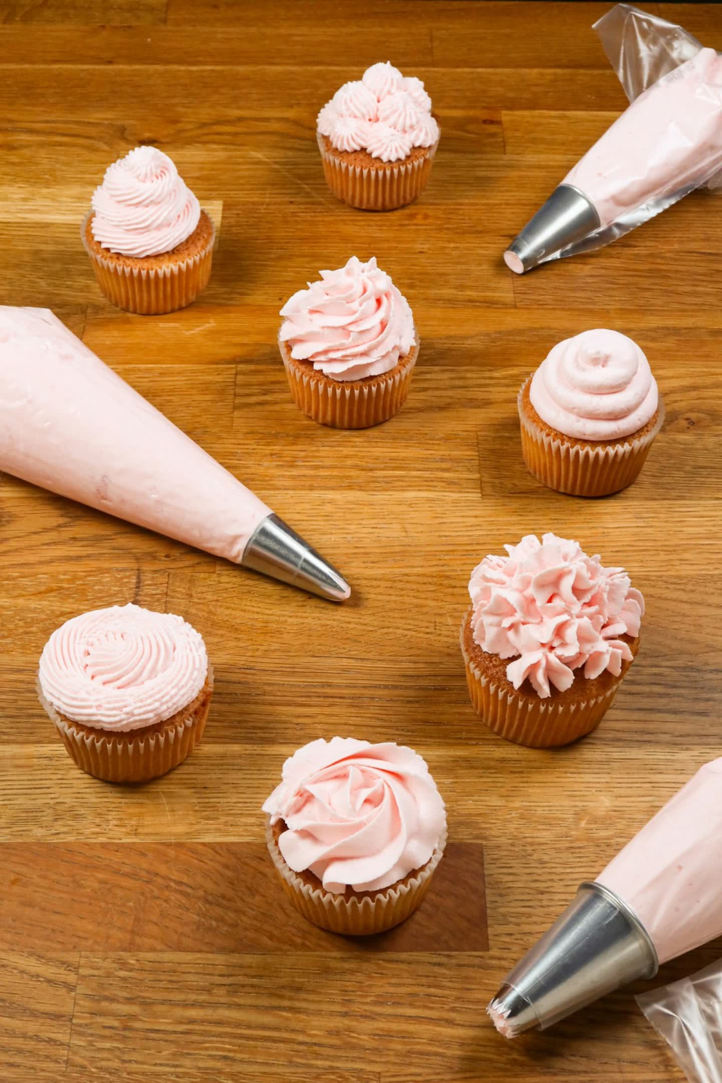 Box of freshly piped cupcakes with soft pink buttercream swirls